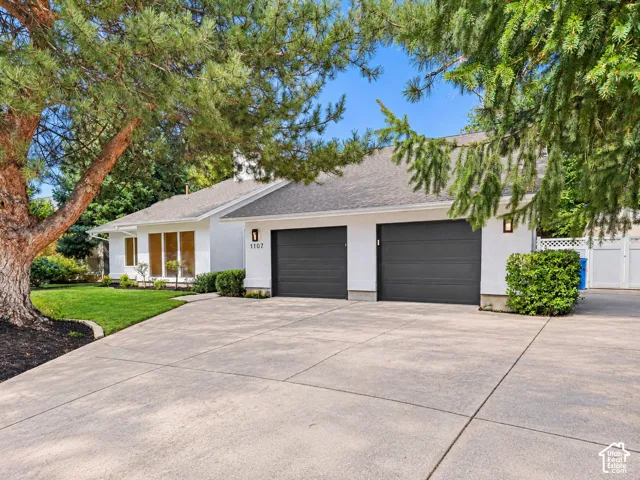 Exterior featuring a white stucco finish, dual dark-toned garage doors, and a concrete driveway