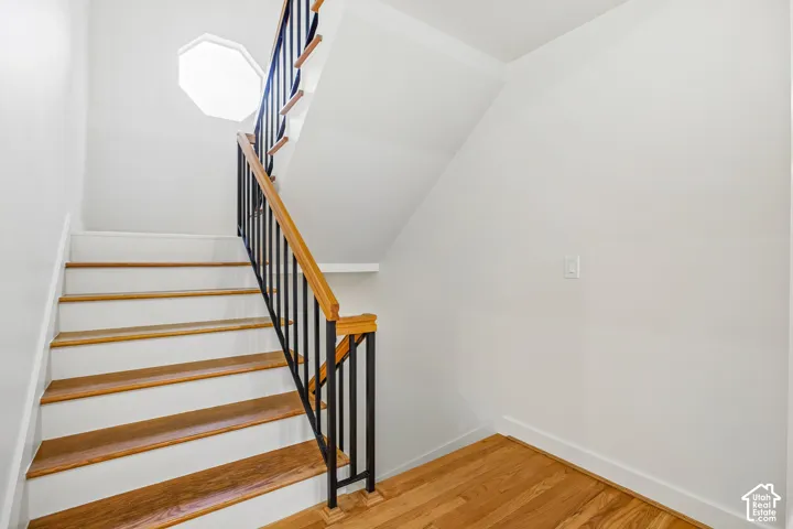 Hardwood treads with white risers, black metal balusters, and a natural wood handrail