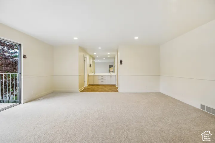 Recessed lighting, light-toned carpeting, built-in cabinetry, and a full-width mirror