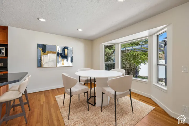 Recessed lighting, wood-finish flooring, bay window, light wood cabinetry, and a dark countertop