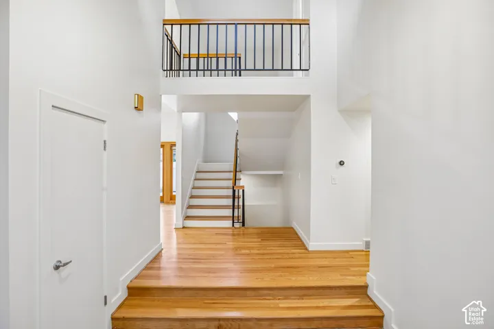 Multi-level interior featuring a staircase, wood-finish flooring, white walls, and a second-story landing with black metal railing