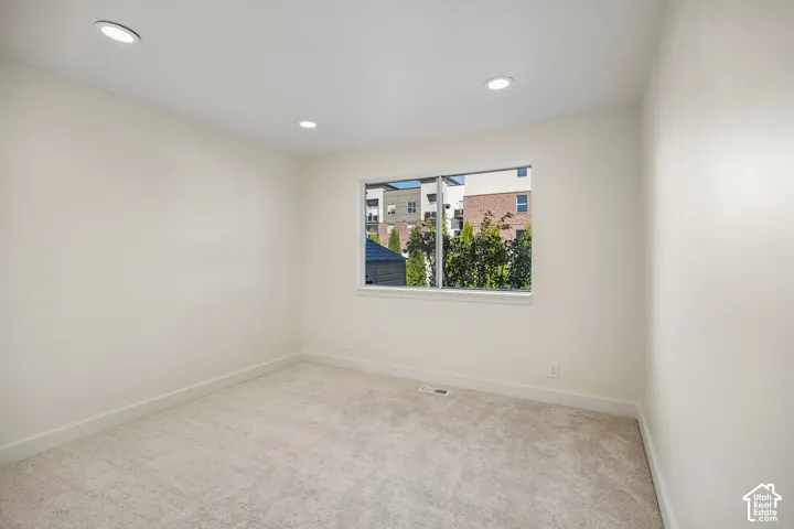Recessed ceiling lighting, a single window, light-toned carpeting, and light-painted walls