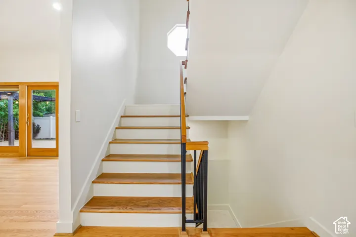 Hardwood stairs with white risers, contemporary metal and wood railing, and an octagonal window