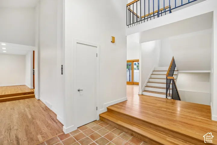 Two-story foyer featuring a staircase with black metal balusters and wood handrail, wood-finish flooring, and recessed lighting