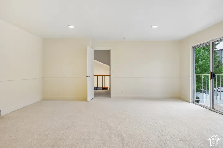 Recessed ceiling lighting, light-toned carpeting, neutral wall finishes, sliding glass doors, and a balcony with white railings