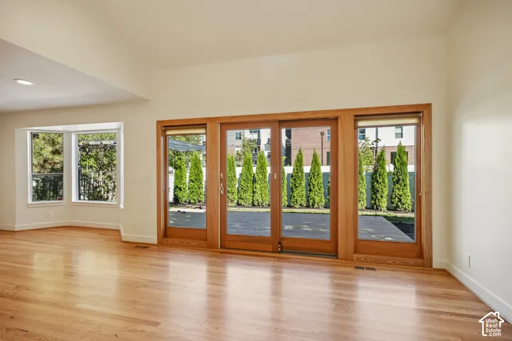 Hardwood flooring, bay window, vaulted ceiling, recessed lighting, and wooden sliding doors