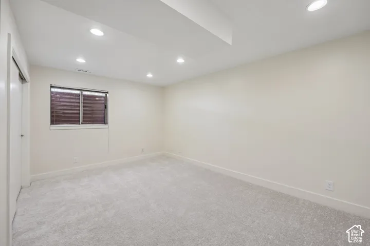 Recessed lighting illuminating the light-colored walls and grey carpeting