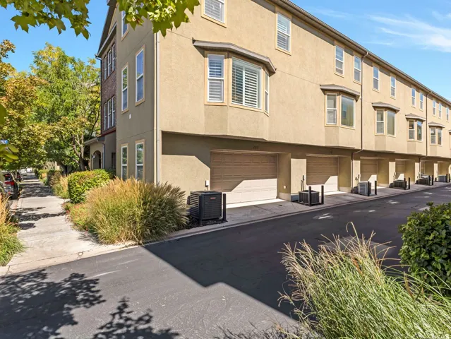 Multi-story stucco exterior with multiple bay windows and integrated individual garages
