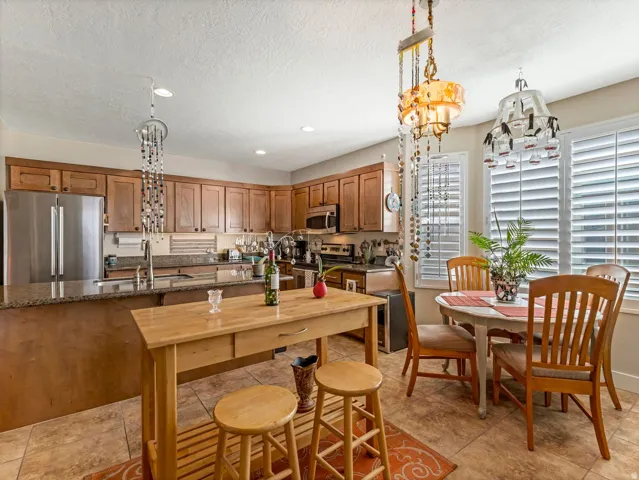 Kitchen featuring wood-finish cabinetry, stainless steel appliances, granite countertops, and tile flooring