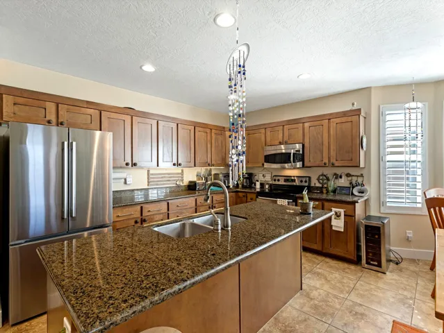 Kitchen featuring wood-finish cabinetry, granite countertops, a stainless steel French door refrigerator, and a double basin sink