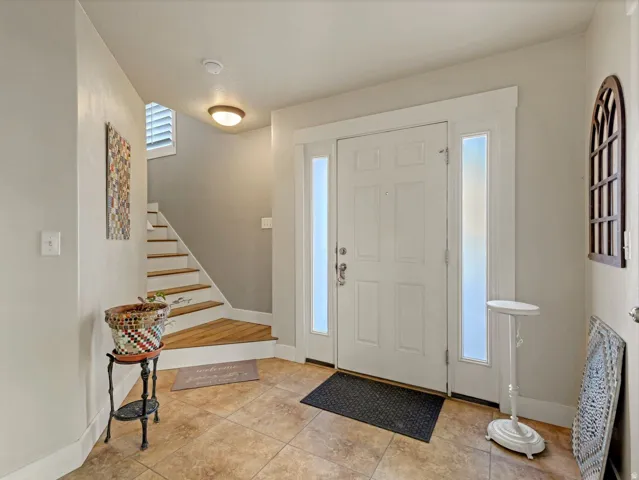 Entryway featuring a paneled door, two sidelight windows, tile flooring, and a staircase with wood-finish treads and white risers