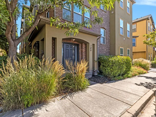 Multistory facade featuring brick and stucco finishes, an arched entry, and a dark paneled door