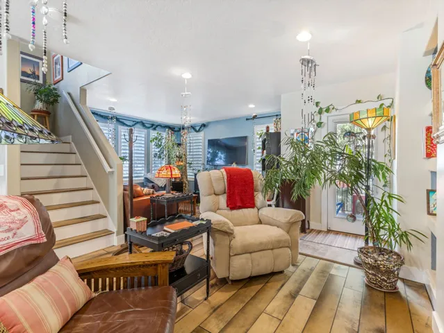 Wood-finish flooring, staircase with painted risers, recessed ceiling lighting, and bay windows with plantation shutters