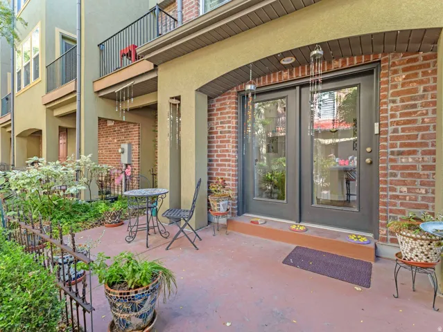 Brick facade with an arched entry, double glass-paneled doors, and a wrought iron balcony