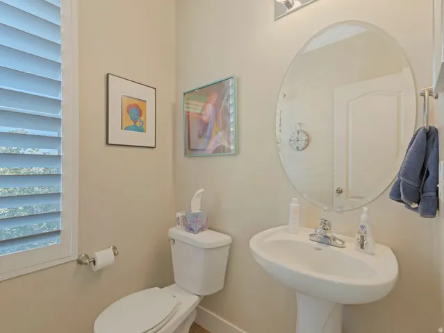 Pedestal sink with chrome faucet, oval mirror, and interior plantation shutters