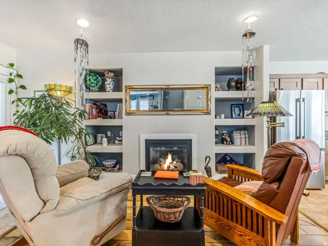 Fireplace with mantel, recessed built-in shelving, recessed lighting, and tile flooring