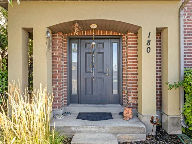 Stucco and brick facade featuring an arched entryway, double-pane front door, and concrete porch