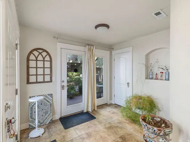 Tile flooring, white paneled doors, recessed architectural niche, and glass-paned exterior door