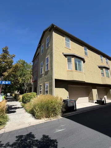 Multi-story stucco exterior with multiple windows, bay window, and attached garages