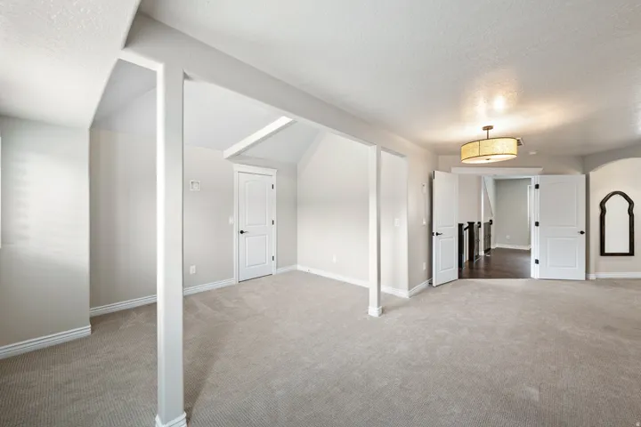 Vaulted ceiling, recessed lighting, carpet flooring, solid core doors, and a decorative ceiling light fixture