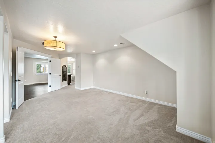 Plush carpeted flooring, neutral wall tones, recessed lighting, double doors, and a ceiling-mounted fixture