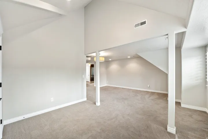 Spacious room featuring vaulted ceilings, recessed lighting, and soft carpeting