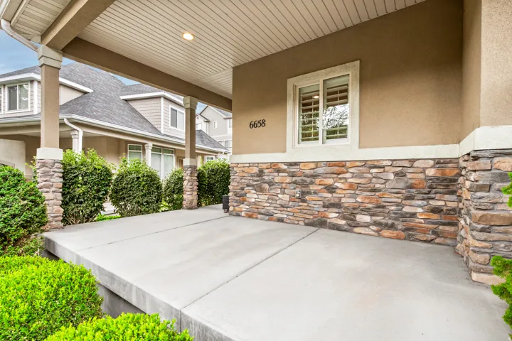 Expansive covered porch featuring stone veneer accents and stucco siding