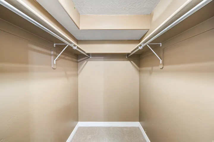 Neutral-toned walls with ceiling-mounted shelving and hanging rods