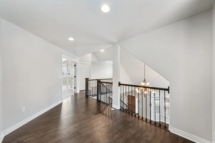 Wood-finish flooring, recessed lighting, wrought iron railing, white trim, and a paneled door