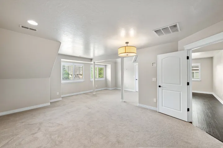 Carpeted flooring, recessed lighting, multiple windows with shutters, drum pendant light fixture, and a paneled interior door
