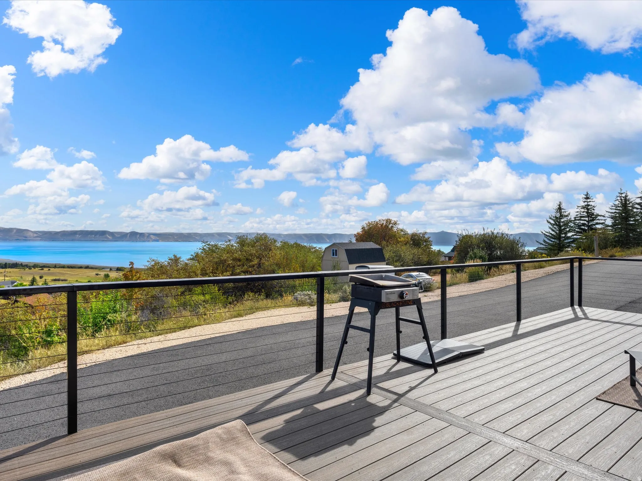 Spacious outdoor deck with composite decking and cable railing, offering expansive water scenery