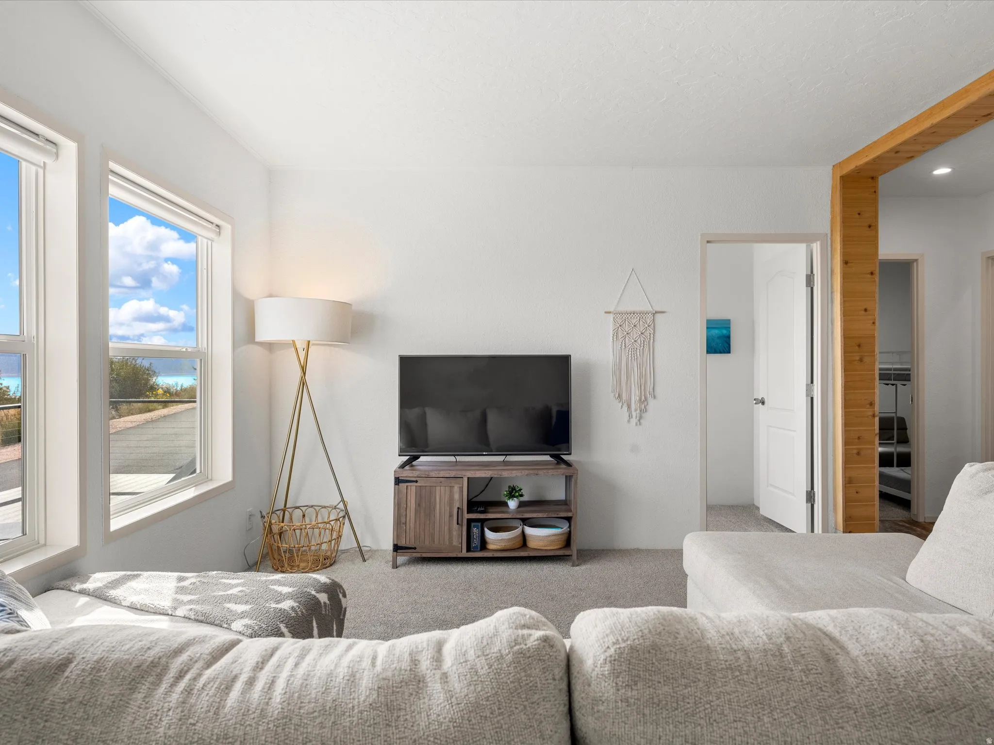Recessed lighting, wood-finish structural beam, white trim, and light grey carpeting