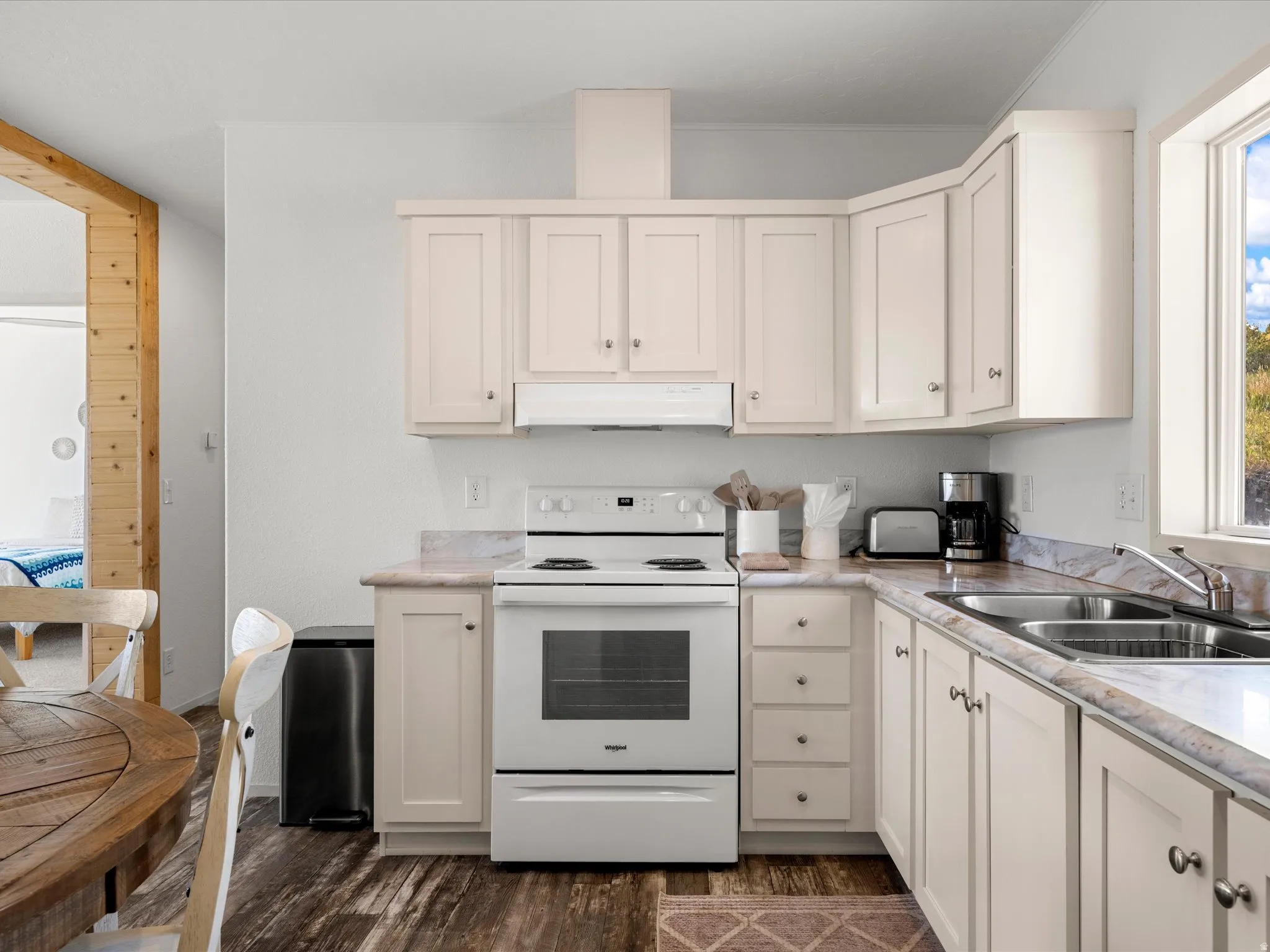 Kitchen featuring white cabinetry, a white electric range, double basin sink, and wood-finish flooring