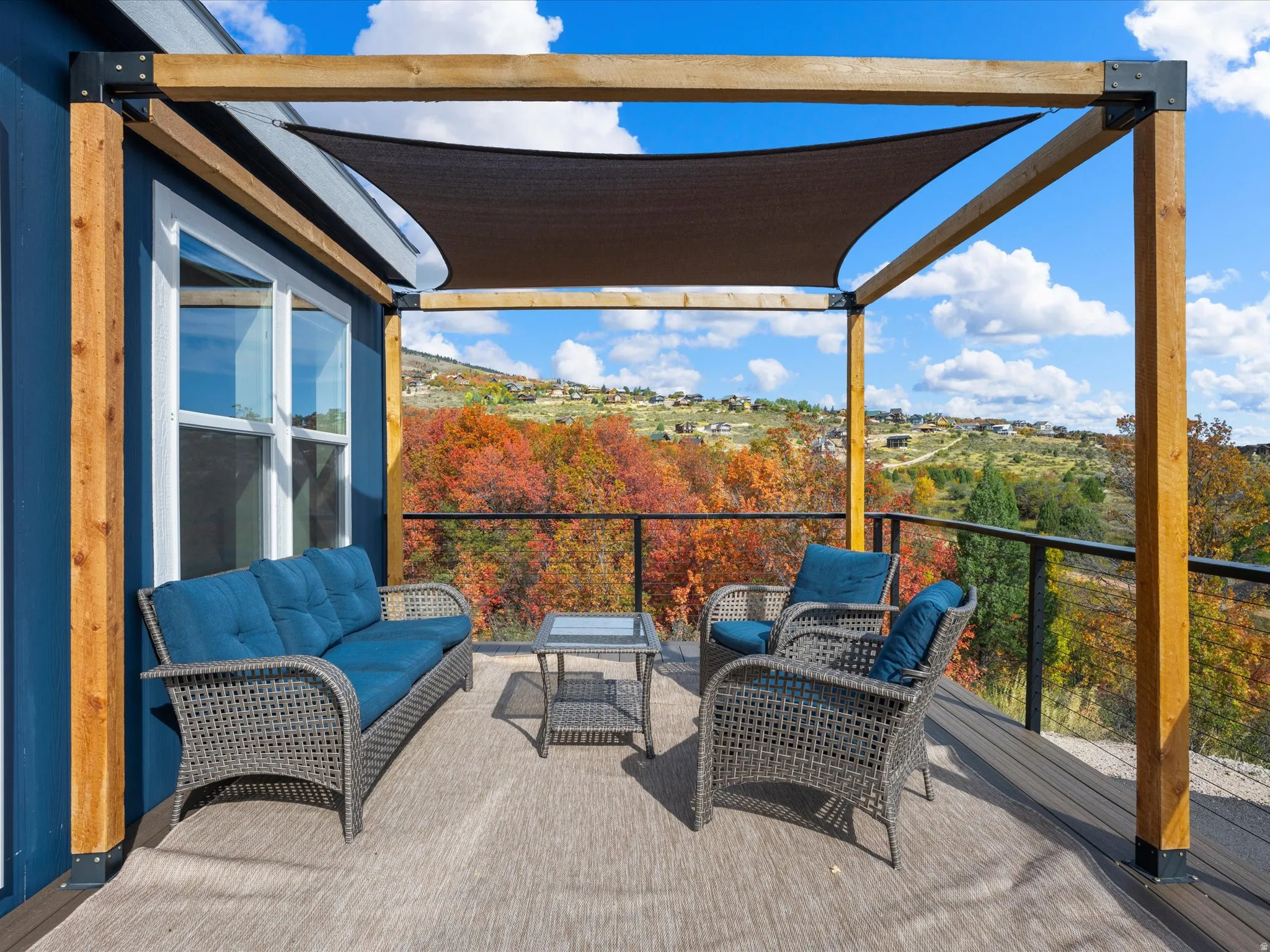Expansive outdoor deck featuring a shade canopy, robust wooden pergola, and metal railing