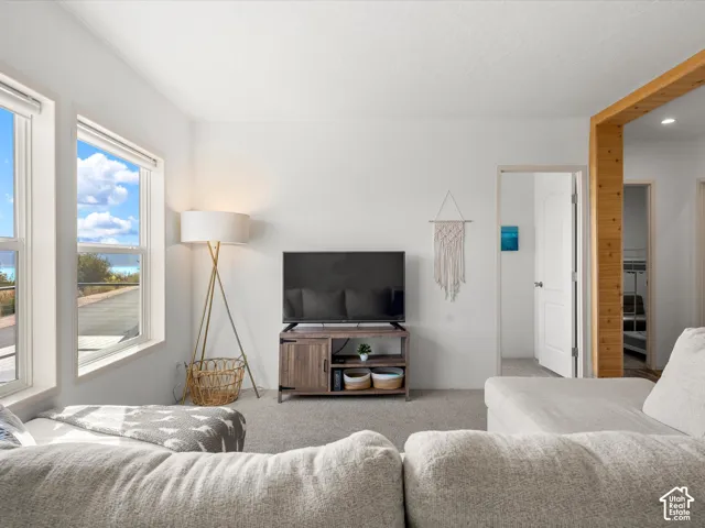 Recessed lighting, wood-finish structural beam, white trim, and light grey carpeting