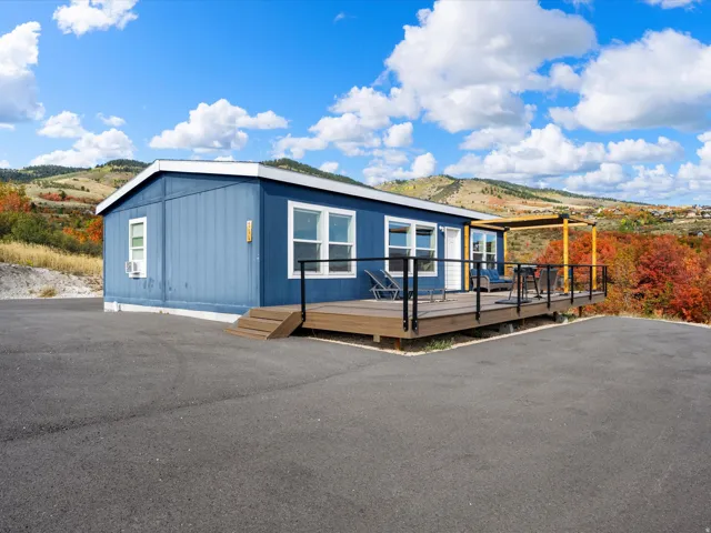 Blue exterior siding with white trim, elevated wood-finish deck with black railings