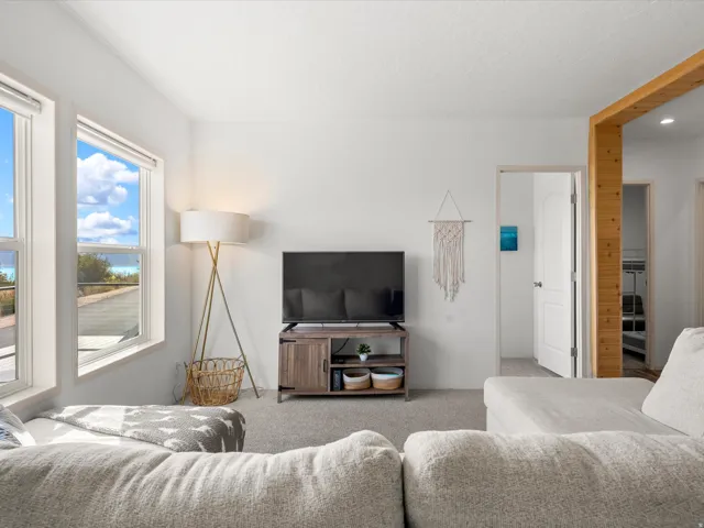 Recessed lighting, wood-finish structural beam, white trim, and light grey carpeting