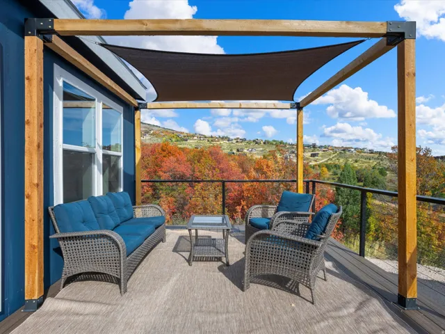 Expansive outdoor deck featuring a shade canopy, robust wooden pergola, and metal railing
