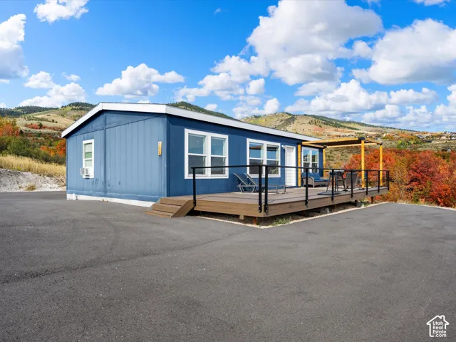Blue exterior siding with white trim, elevated wood-finish deck with black railings
