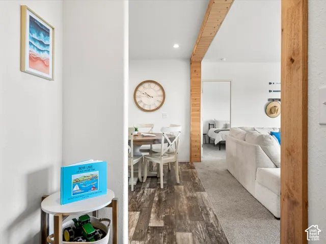 Open-concept living space featuring wood-finish flooring, exposed wood beams, and recessed lighting