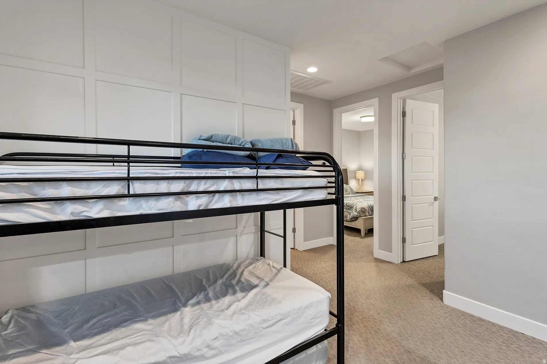 White paneled wall detail, light gray wall color, light tan carpeting, white interior doors, and recessed ceiling lighting