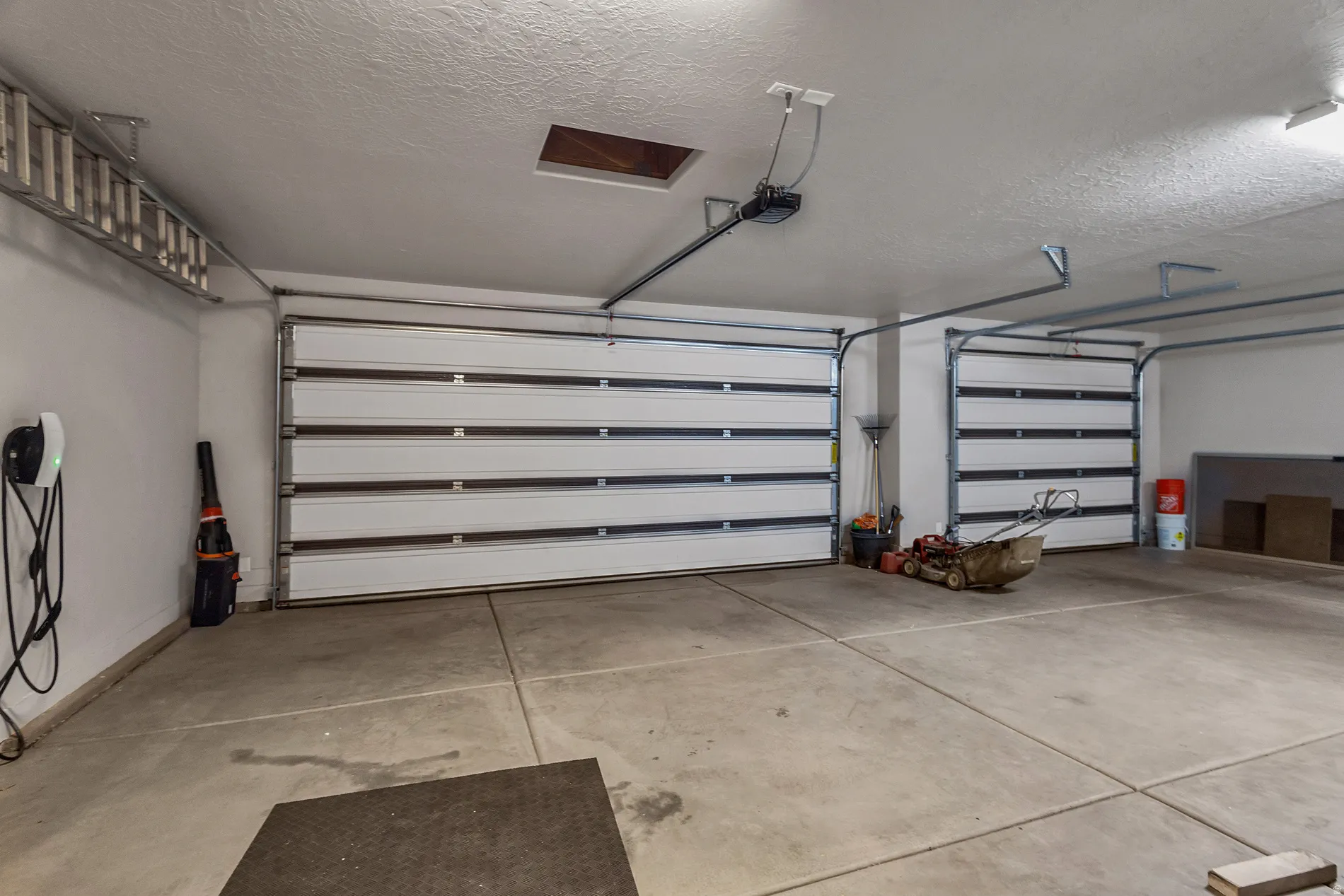 Concrete flooring with two white sectional garage doors