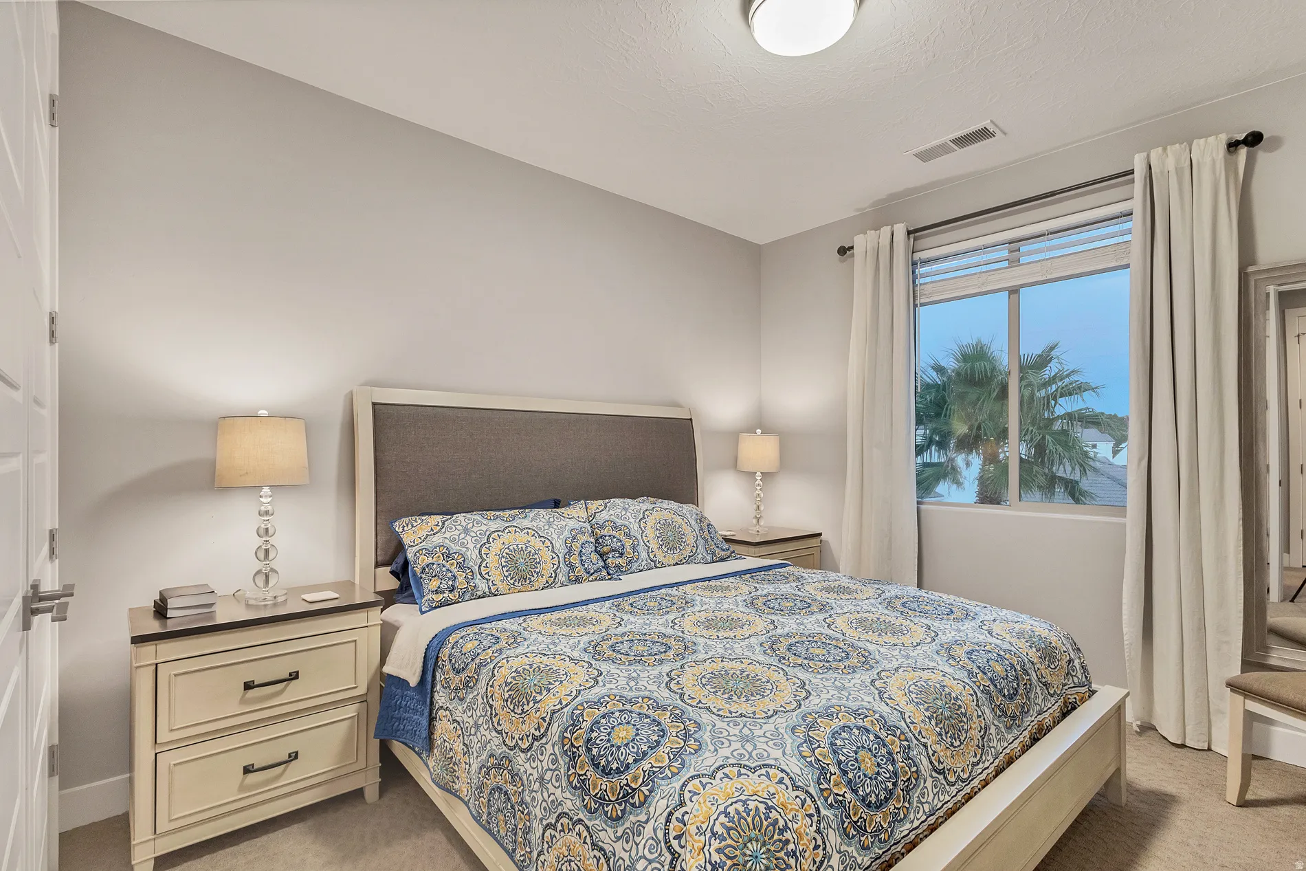 Neutral wall color, window with exterior scenery, carpeted flooring, and a modern flush-mount ceiling light