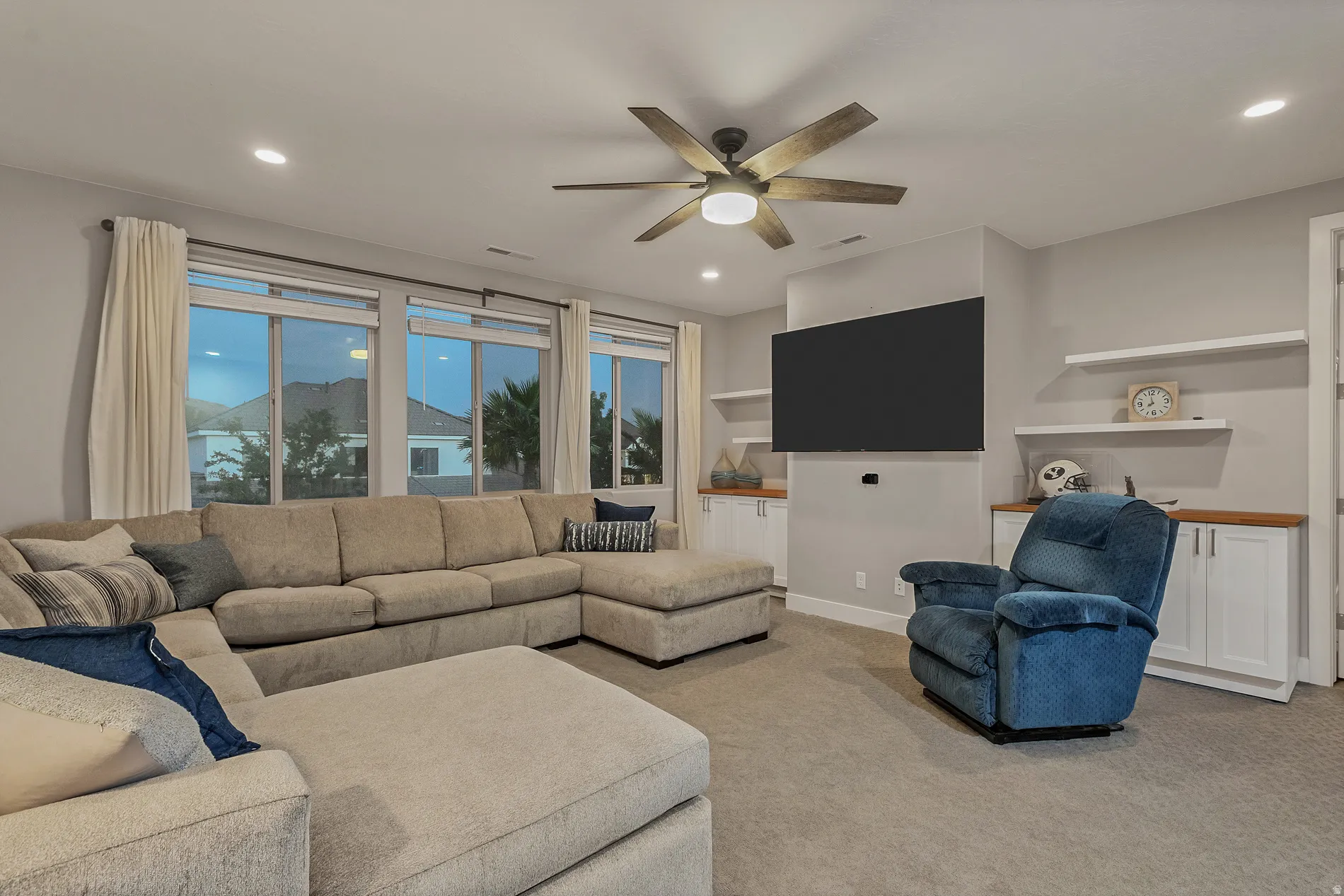 Recessed lighting, wood-finish ceiling fan, multiple windows, built-in cabinetry with wood-finish countertops, and floating shelves