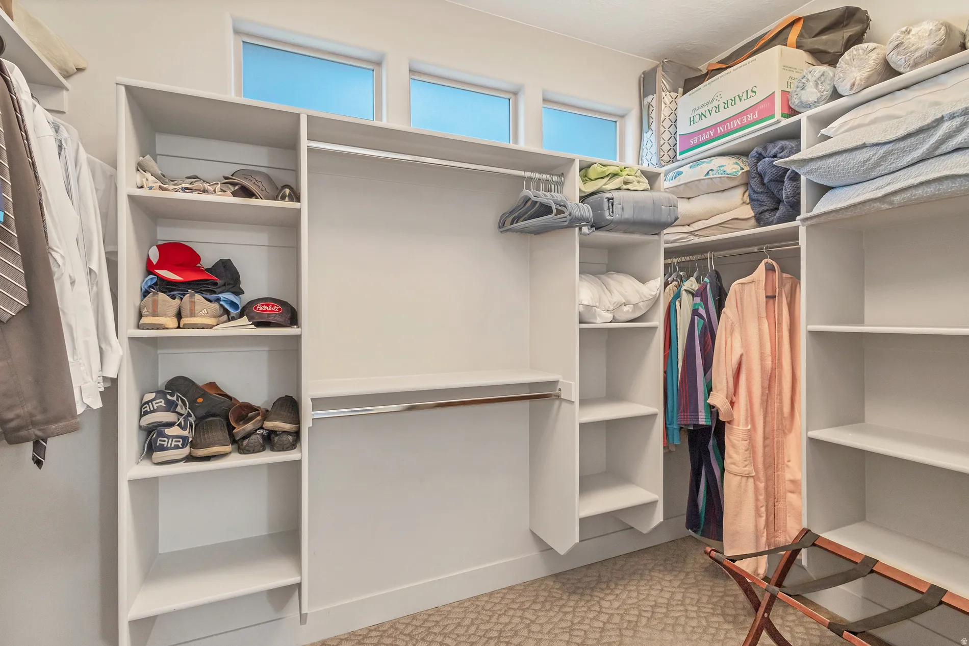 Built-in closet system with multiple shelving units, integrated hanging rods, and transom windows