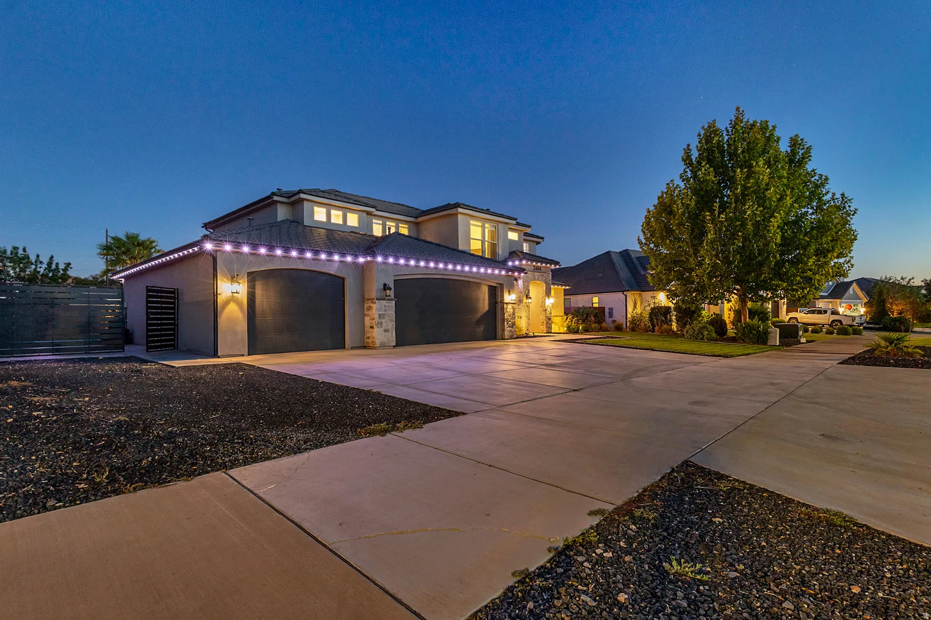 Stucco exterior with stone accents, arched garage doors, a multi-story design, and a concrete driveway