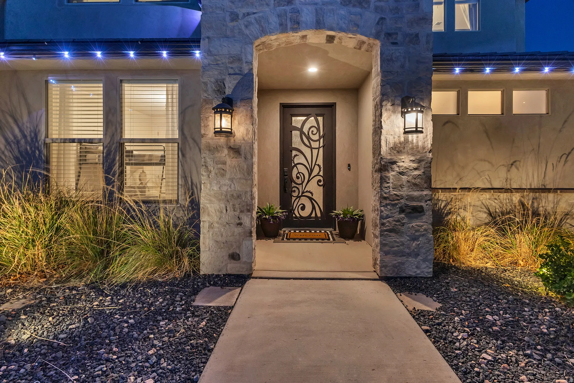 Stone-clad entry archway featuring an ornate wrought iron front door