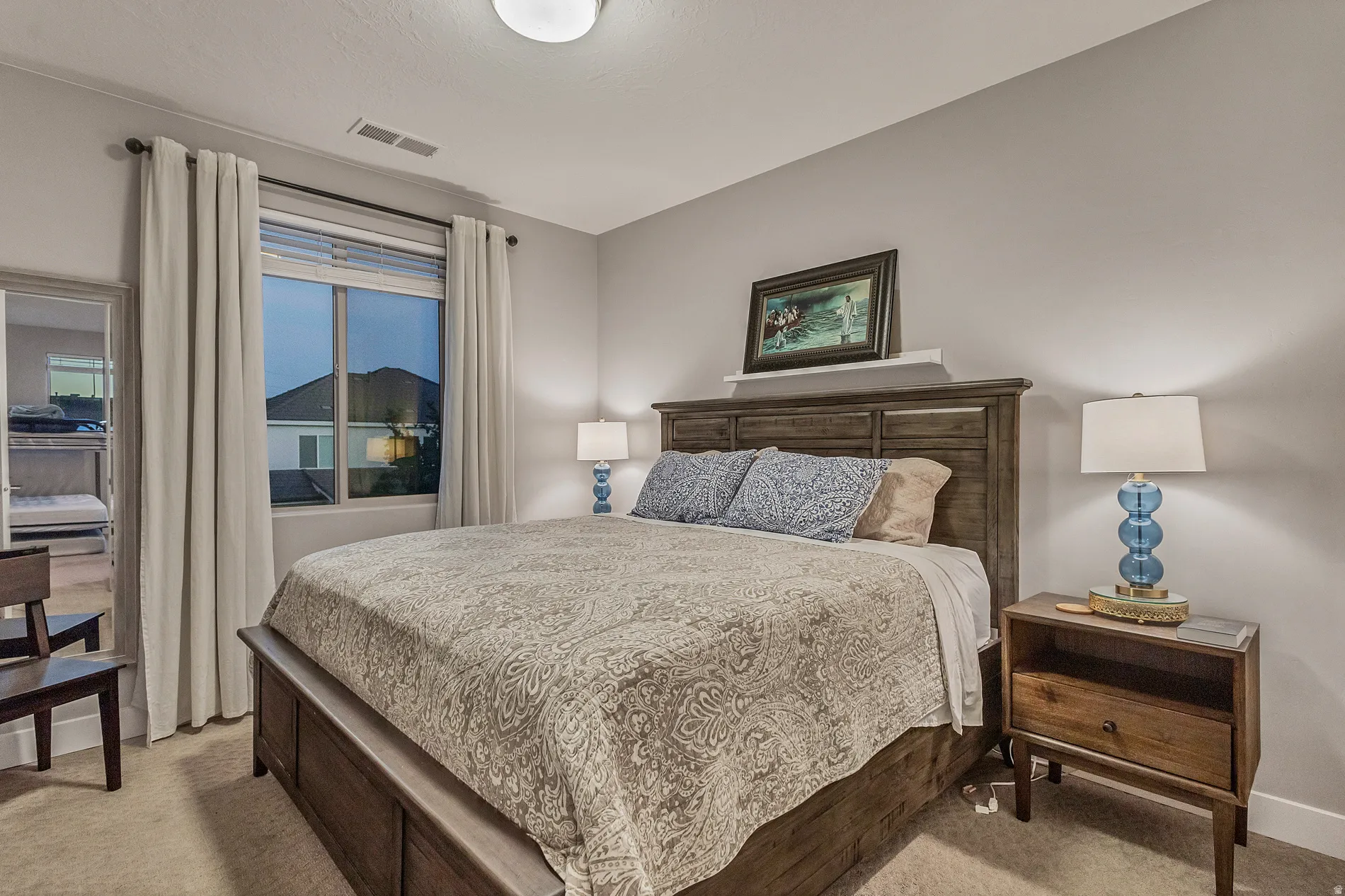 Recessed window with drapes, wood-finish headboard, built-in wall shelf