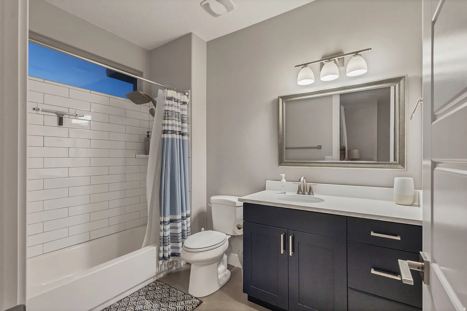 Built-in bathtub with subway tile surround, transom window, and brushed nickel fixtures