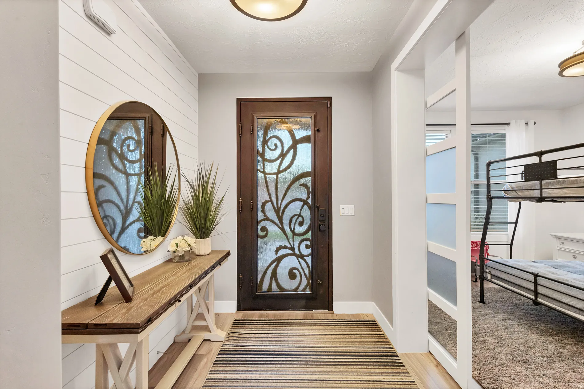 Entryway featuring a decorative wrought iron entry door, shiplap accent wall, and wood-finish flooring